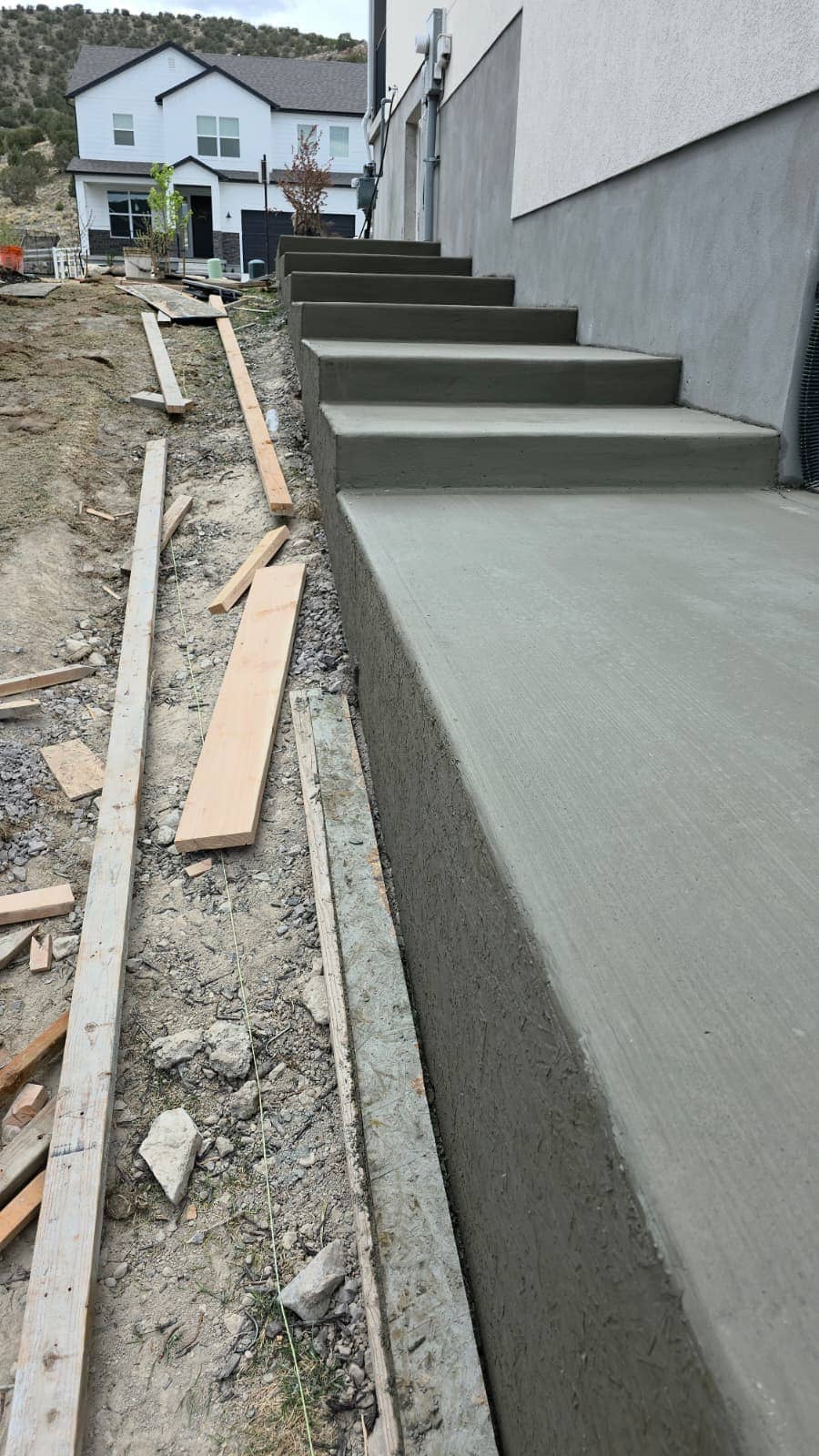 Freshly poured concrete steps and a landing beside a stuccoed home in the Utah foothills, still in its timber forms