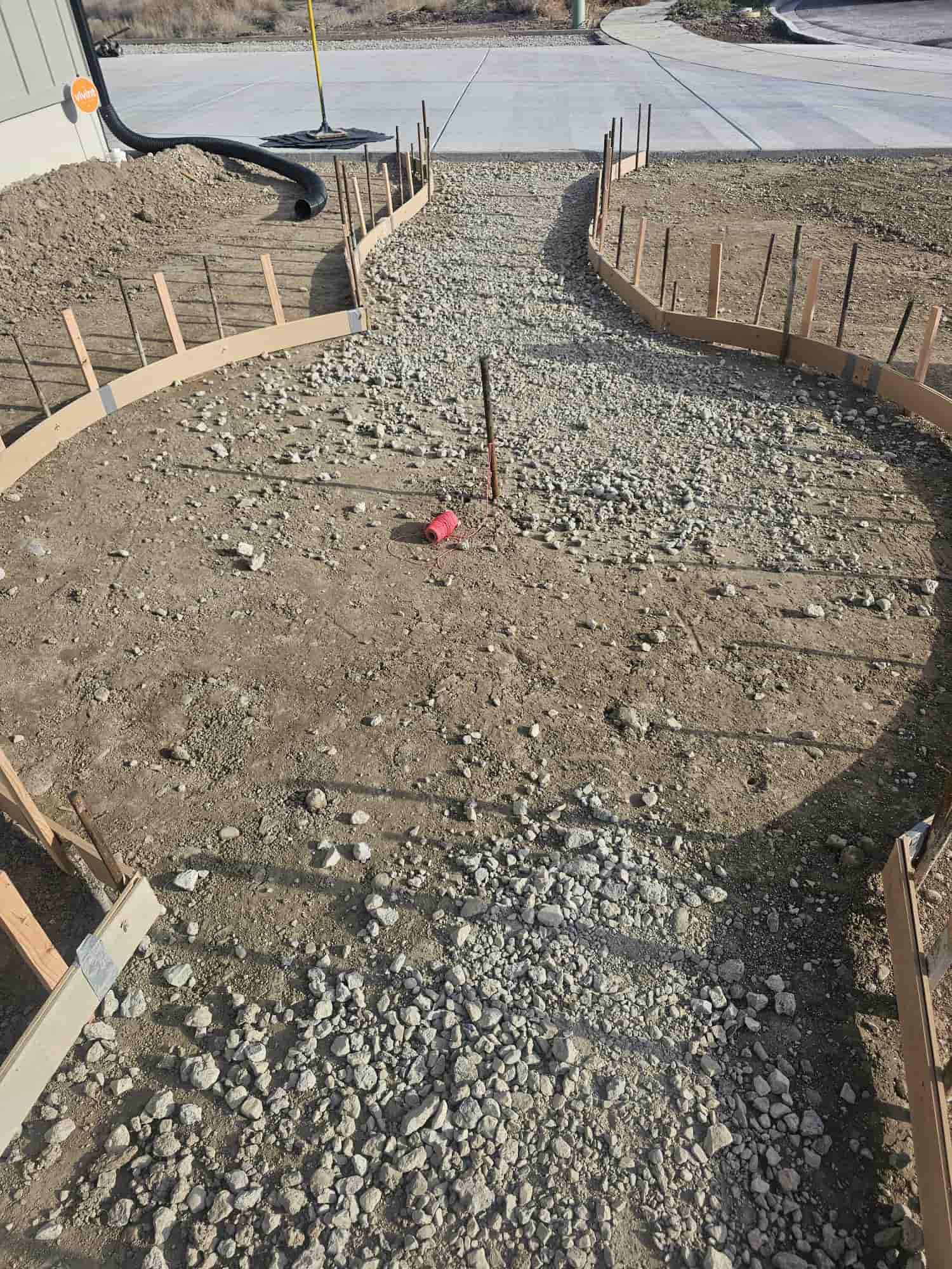 Curved timber forms staked along a gravel base, laying out a walkway before the pour