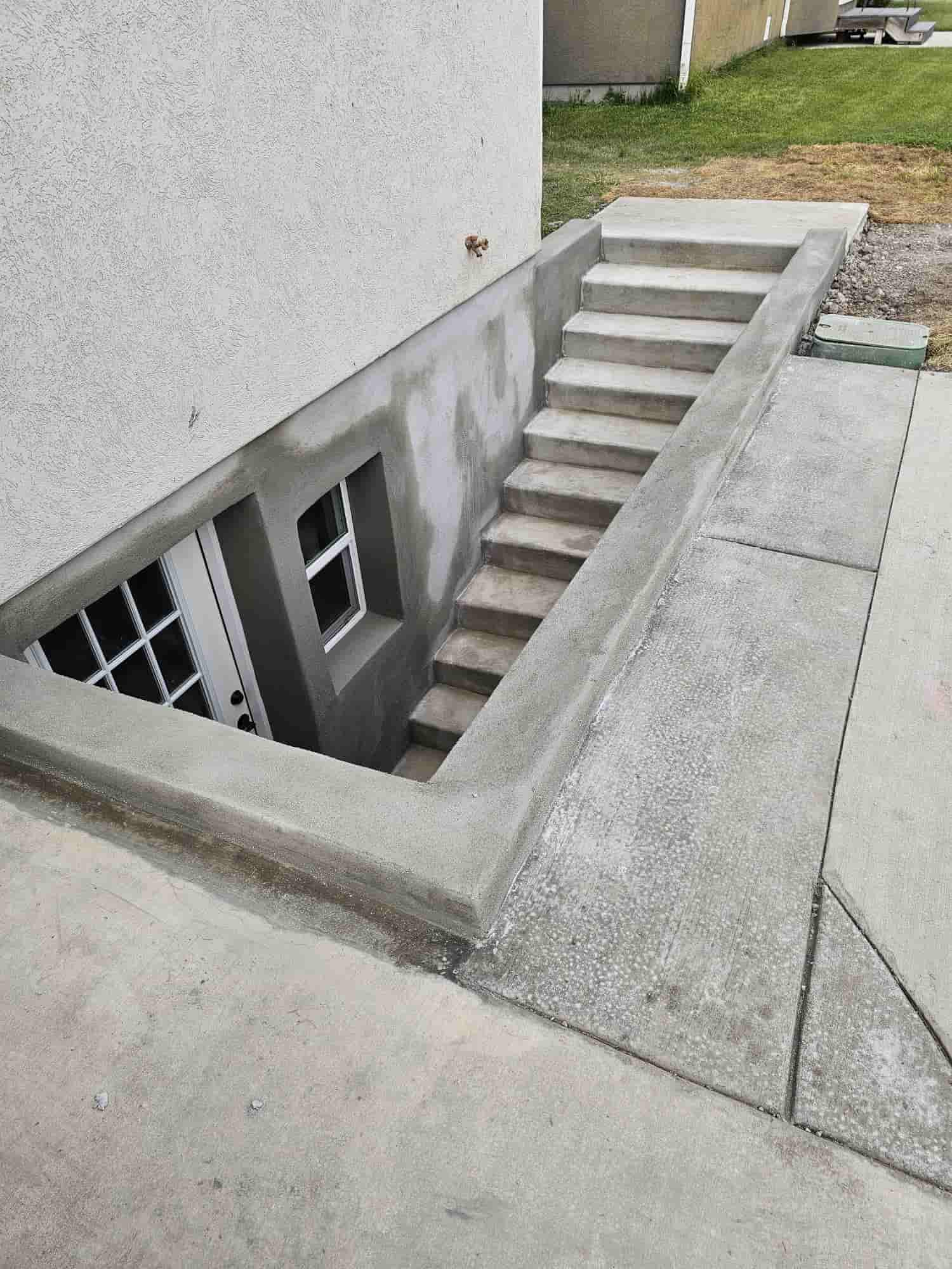 Concrete stairs descending to a basement entry with a window alongside