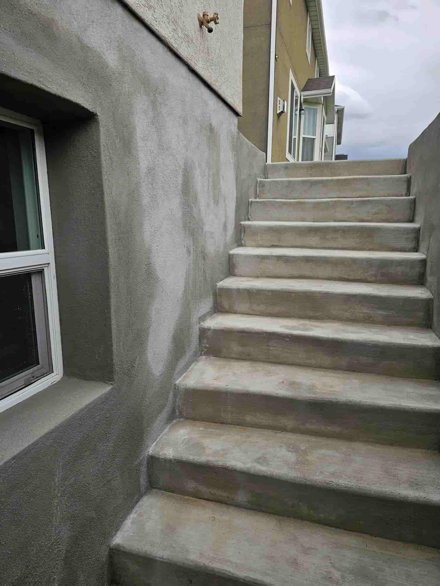 Concrete entry steps rising to a doorway in a stuccoed wall