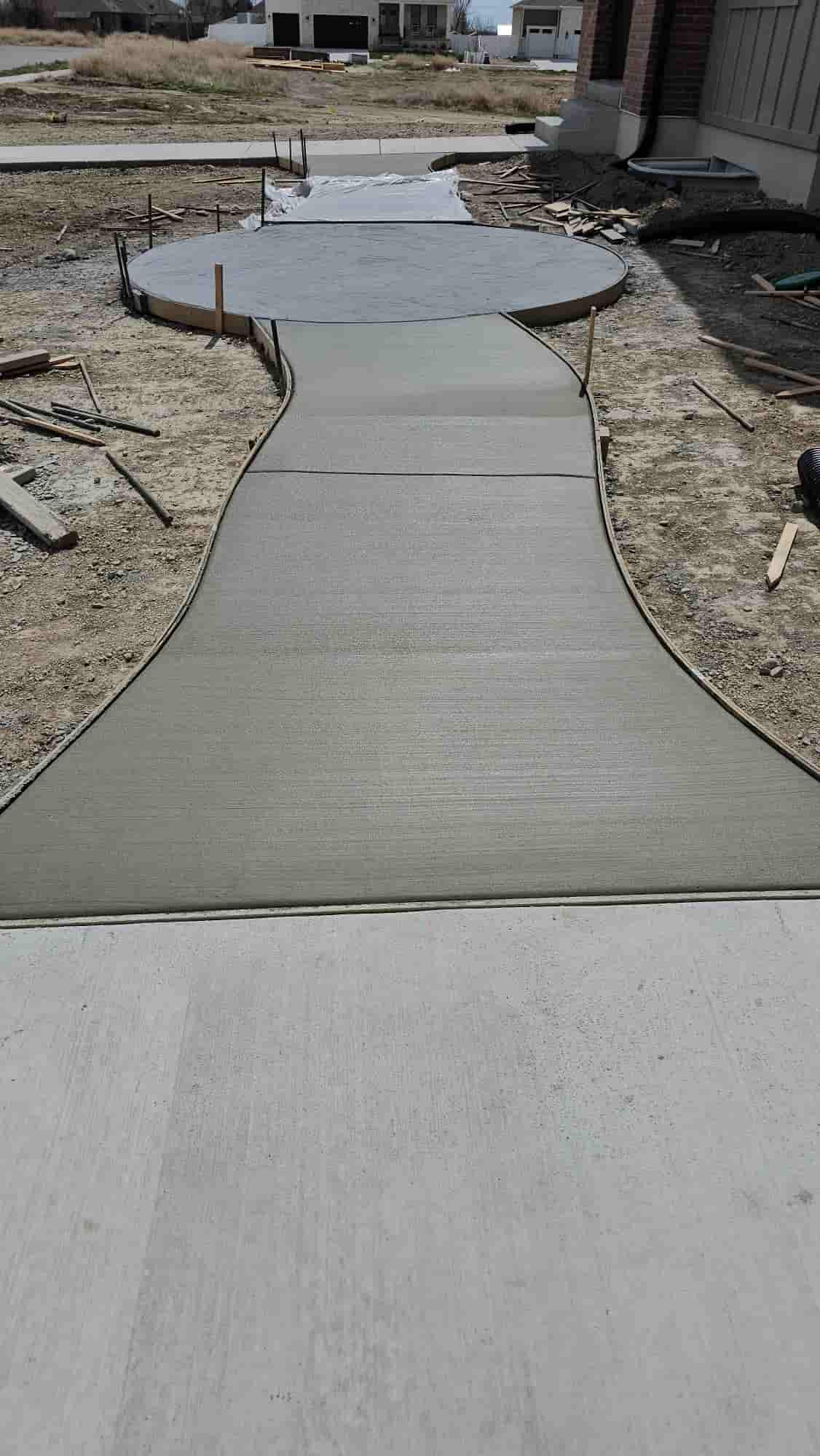 Curved concrete path crossing a graded yard toward a new build