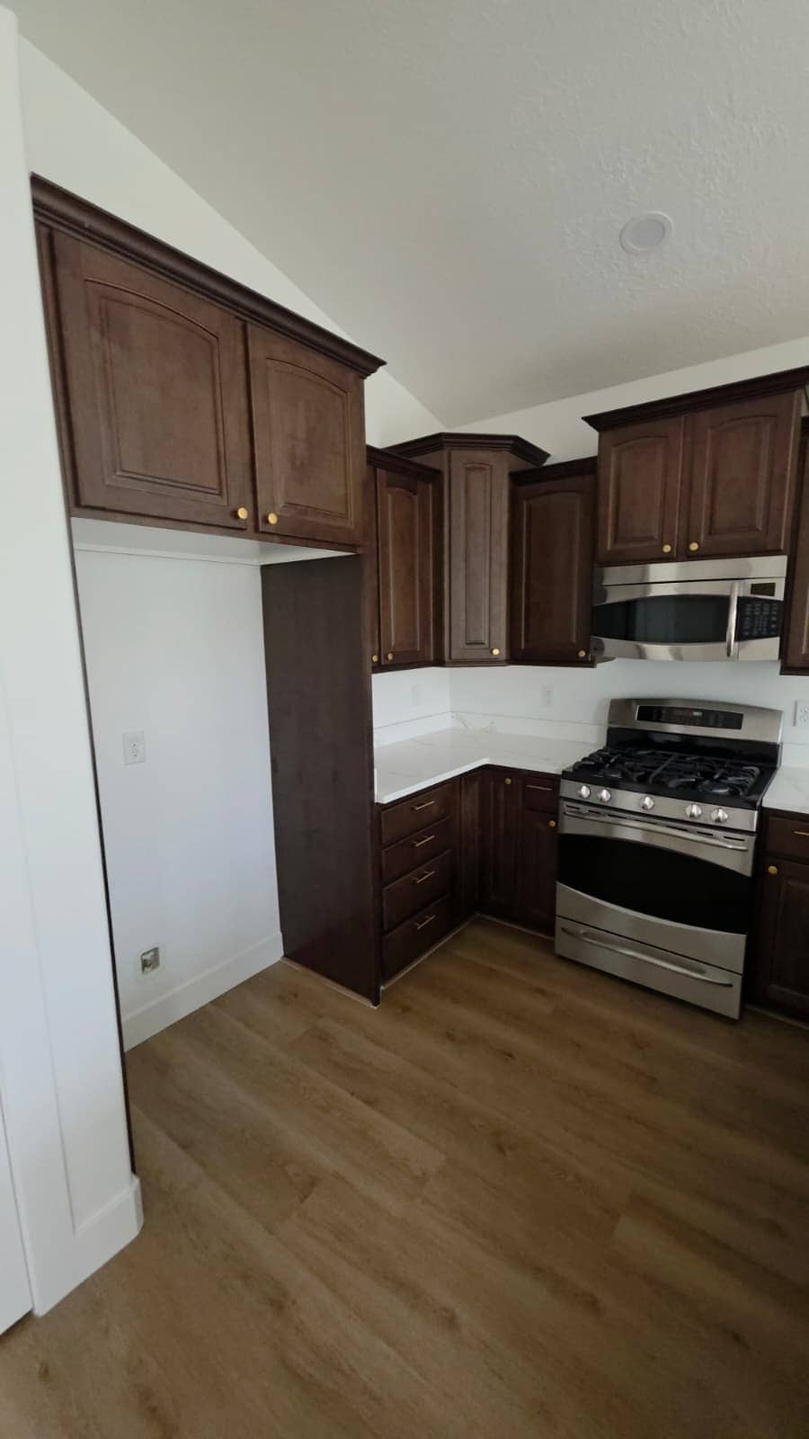 Finished kitchen remodel with dark wood cabinets, a stainless gas range and a vaulted ceiling