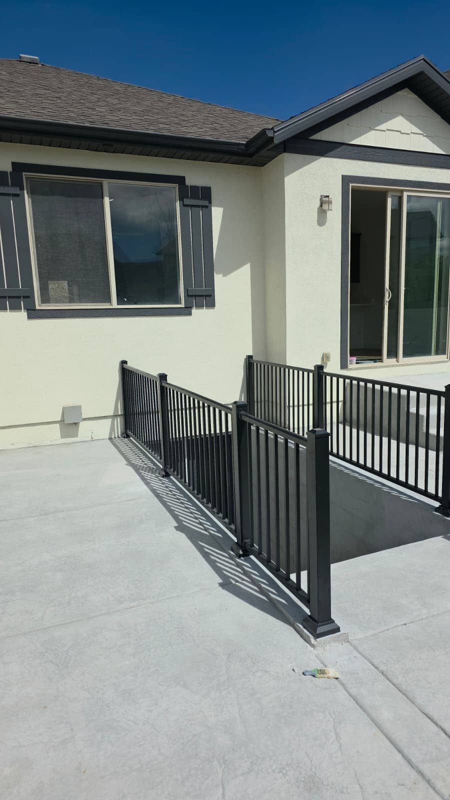 Exterior basement stairwell with black railings beside a stucco house