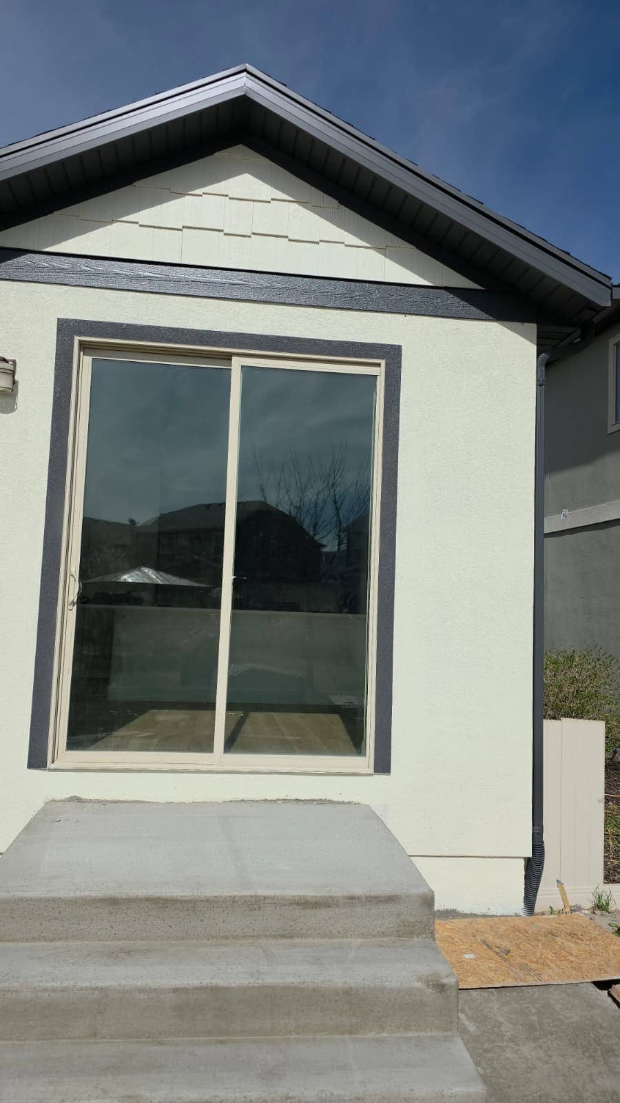 Stucco addition with a sliding glass door and new concrete steps