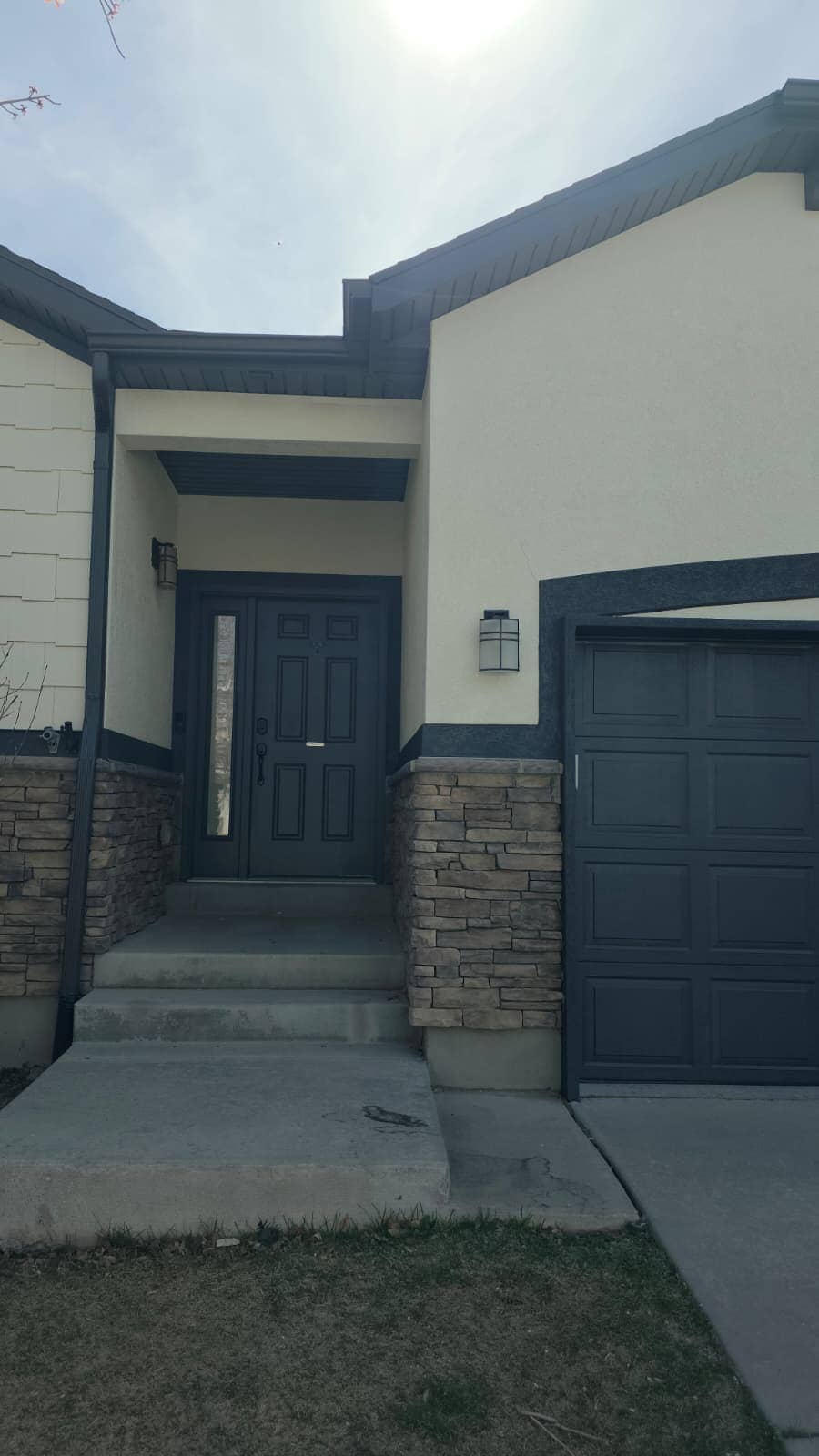 Front entry of a stucco and stone house with concrete steps and porch