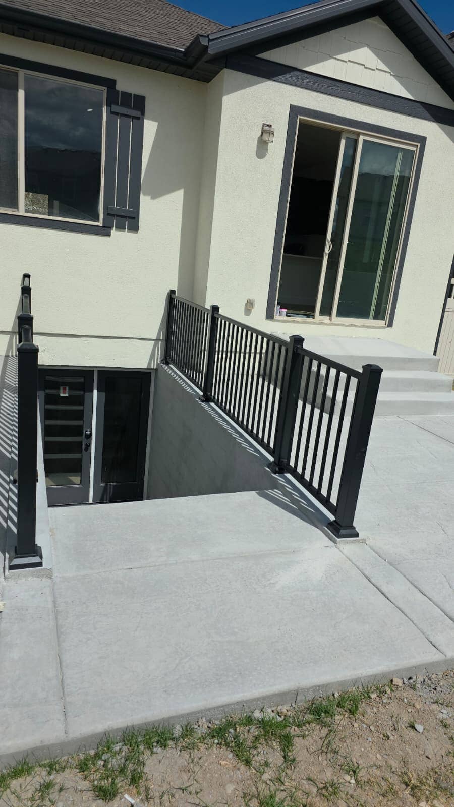 Finished exterior basement stairwell with black railings and a concrete apron