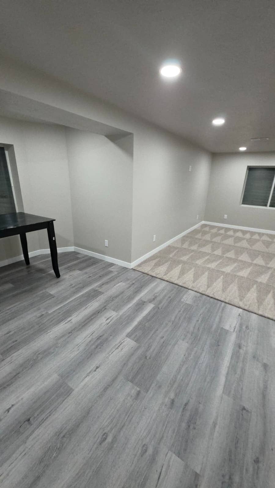 Finished basement family room with vinyl plank flooring, carpet, recessed lights and a soffit