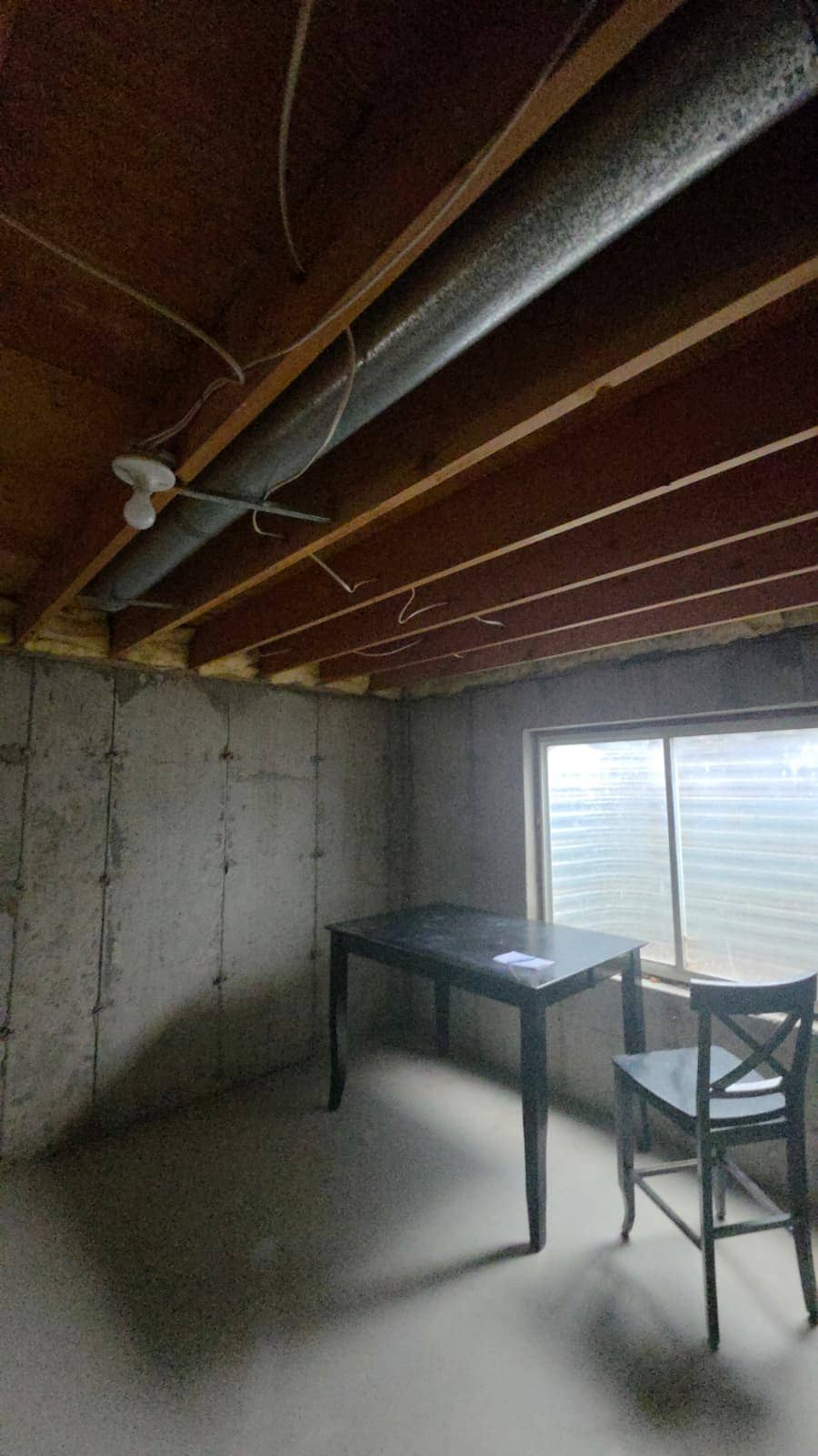Unfinished basement corner with exposed joists, ductwork and wiring