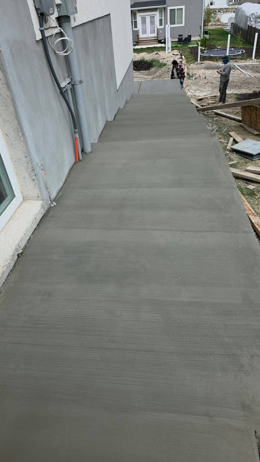 Long concrete walkway running along the side of a house to the back yard